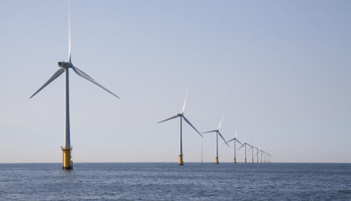 Imagem de diversos aerogeradores na água para simbolizar a energia eólica offshore